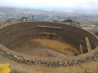 Wasserbecken im Bau vor dem Panorama von der bolivianischen Hauptstadt Cochabamba