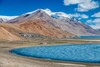 Salzsee mit vereinzelten Häuser vor einem Bergpanorama