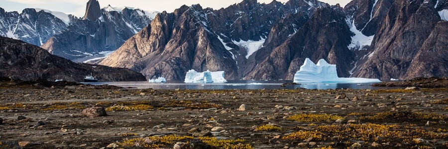 Mit Schnee bedeckte Berge erheben sich aus karger Landschaft