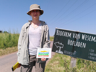 Junge Frau mit Schild vor Ackerfeld 