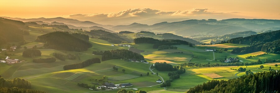 Panoramablick über ein Tal mit naturbelassenen Wäldern sowie Kulturlandschaft