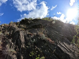 Schwarzes Schiefergestein vor blauem Himmel und strahlender Sonne
