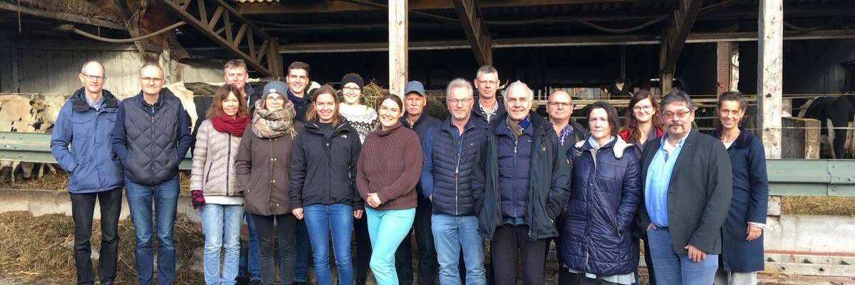 Gruppe von Personen steht vor einem Stall und schaut in die Kamera