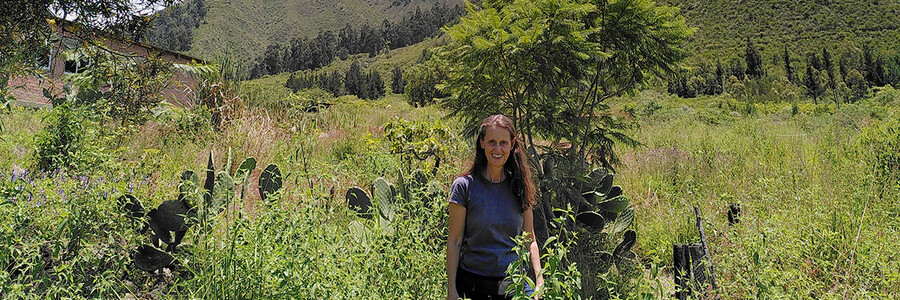 Katja Wiese auf bewirtschafteter Parzelle vor Andenhängen in Bolivien