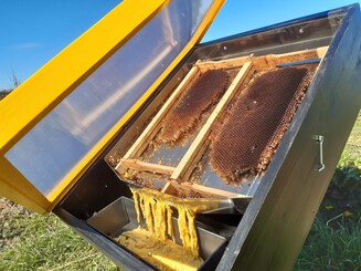 Offener Sonnenwachsschmelzer steht auf einer Wiese