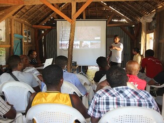 Teilnehmer eines Dynamischen Agroforst Workshops sitzen vor Leinwand