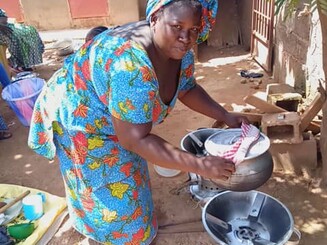 Frau aus Malawi kocht auf einem Holzkohle Kocher