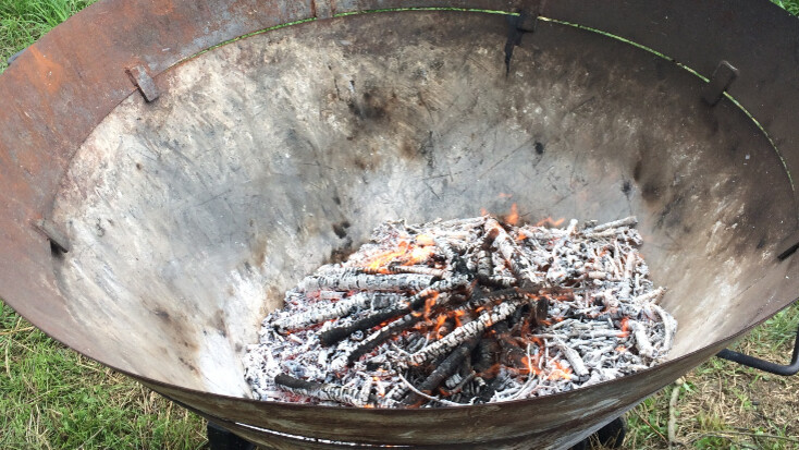 Bereits leicht verkohlte Äste liegen in Kiln zur Herstellung von Pflanzenkohle