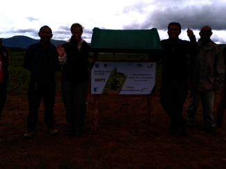 Katja Wiese, die Geschäftsführerin von Naturefund, steht mit Projektpartner neben Schild vor DAF-Parzelle in Ibity auf Madagaskar