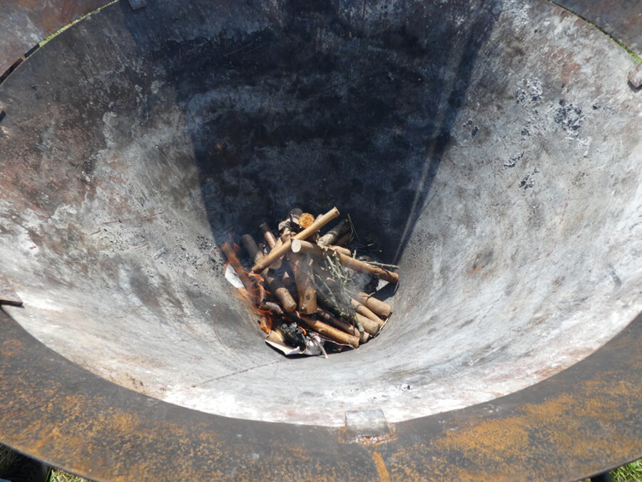 Kleine Äste liegen am Grunde eines trichterförmigen Kilns zur Herstellung von Pflanzenkohle