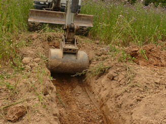 Traktor buddelt Mulde in den Boden